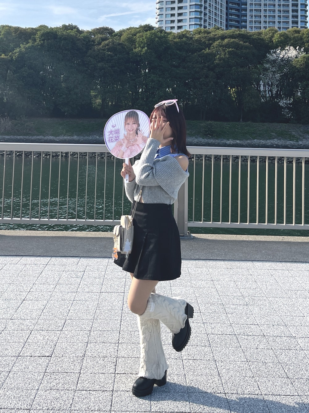 グレー系のトップス、ブラック系のスカート、ベージュ系のショルダーバッグを着用したレディースの春コーディネートの3枚目の写真