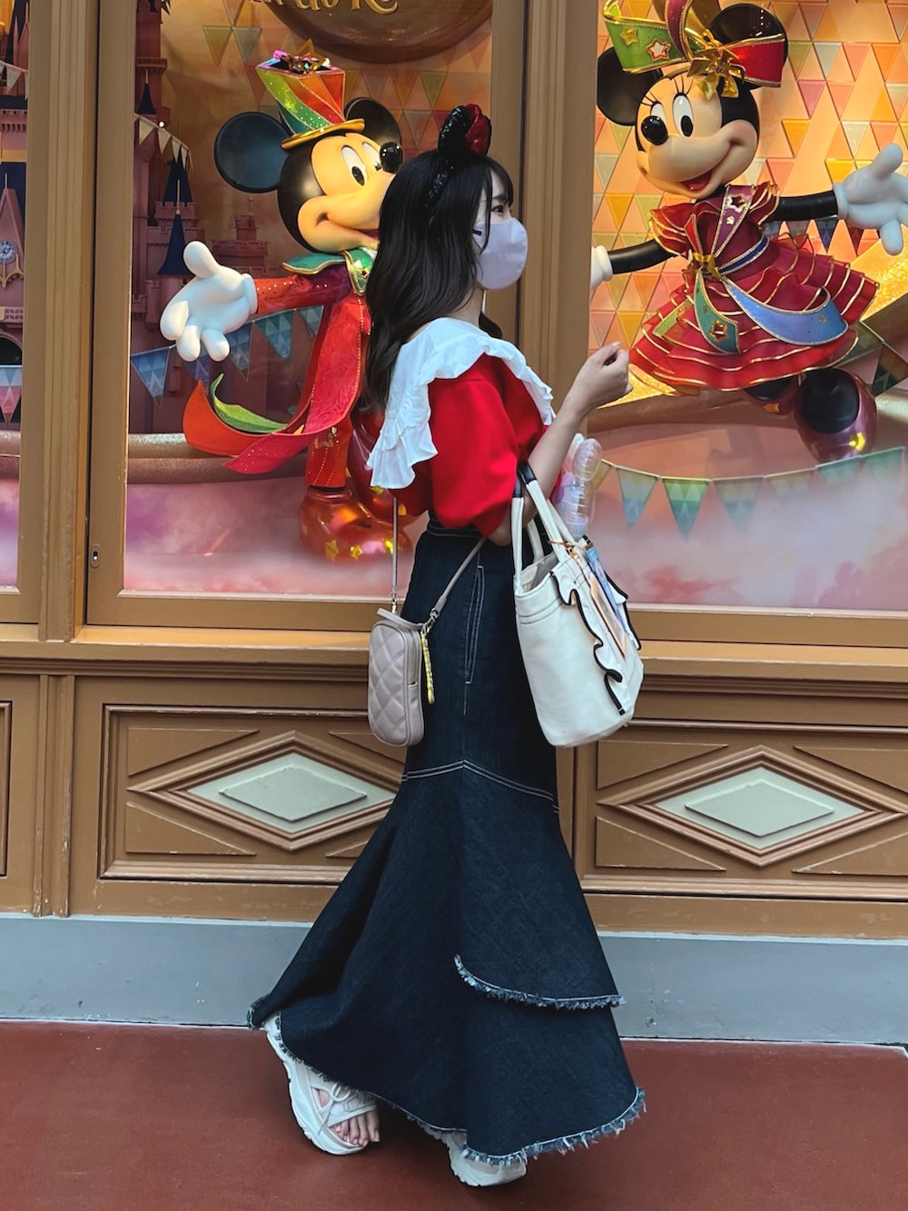 レッド系のスウェット、ホワイト系のトートバッグ、ブルー系のデニムスカートを着用したレディースの春コーディネートの2枚目の写真