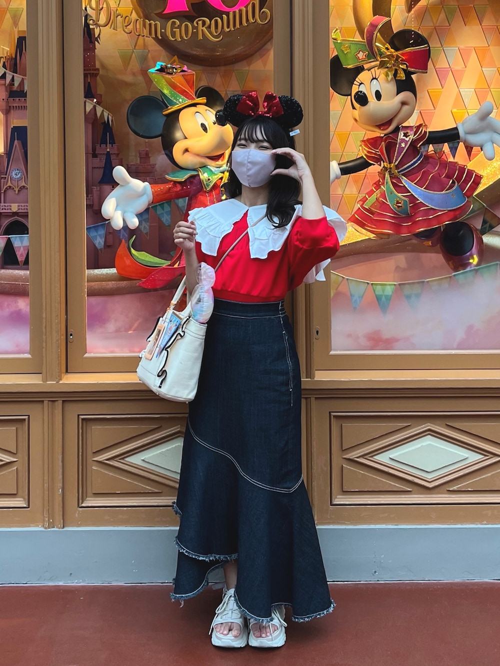 レッド系のスウェット、ホワイト系のトートバッグ、ブルー系のデニムスカートを着用したレディースの春コーディネートの4枚目の写真