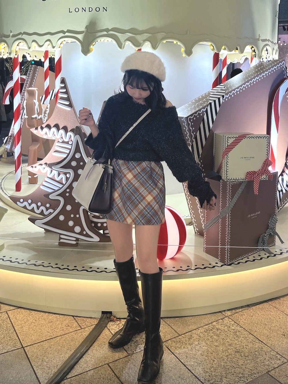 ブラック系のニット/セーター、ブルー系のスカート、ブラック系のブーツを着用したレディースの春コーディネートの2枚目の写真