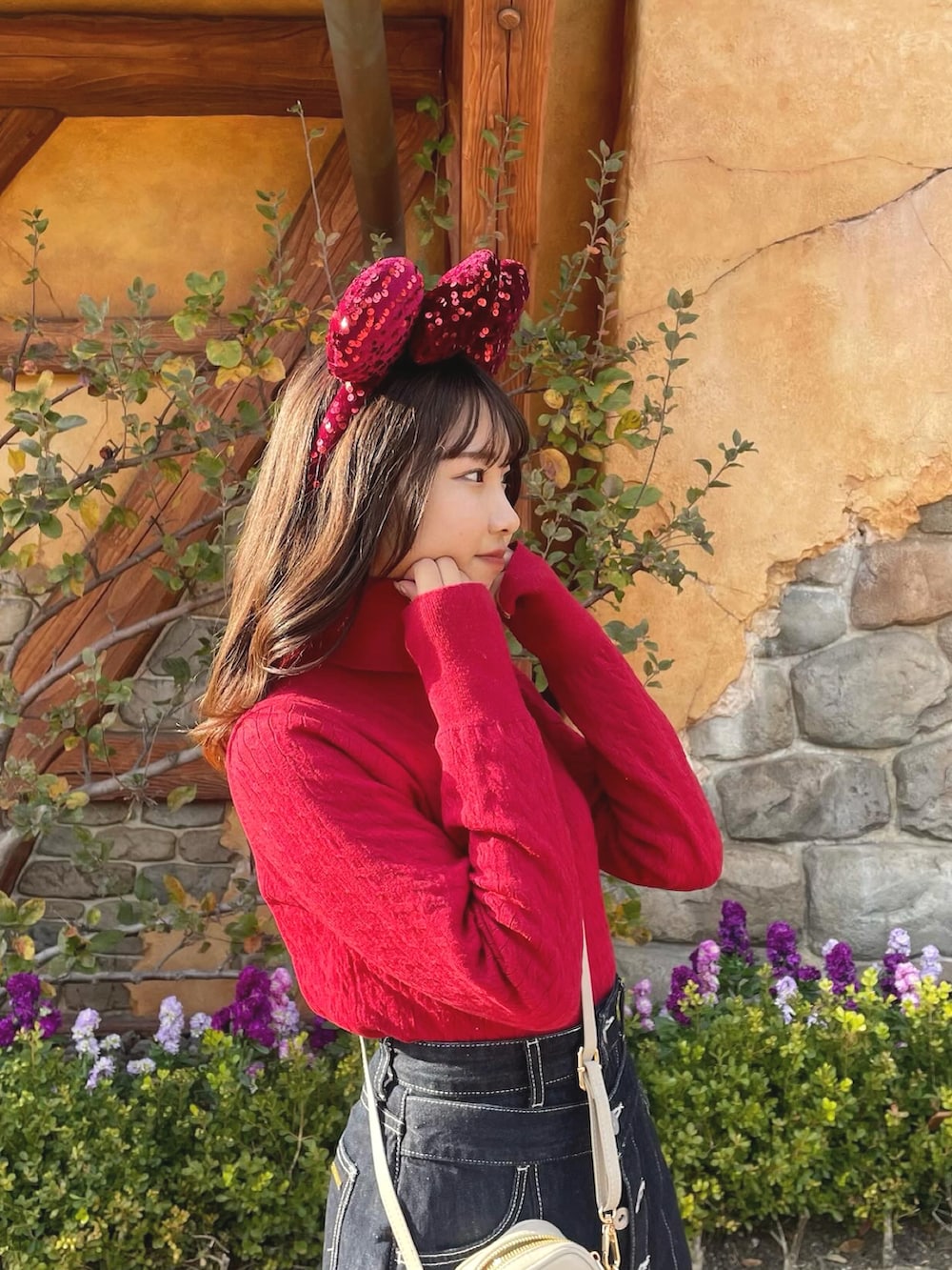 レッド系のニット/セーター、ブラック系のスカート、ブラック系のブーツを着用したレディースの春コーディネートの2枚目の写真