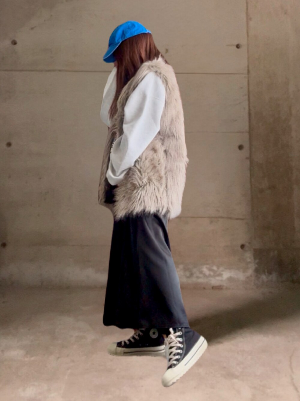 ブラック系のスカート、ブラック系のスニーカー、ベージュ系のベストを着用したレディースの冬コーディネートの2枚目の写真