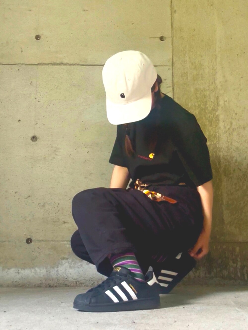 グリーン系のTシャツ/カットソー、ブラック系のスニーカー、ホワイト系のキャップを着用したレディースの夏コーディネートの2枚目の写真