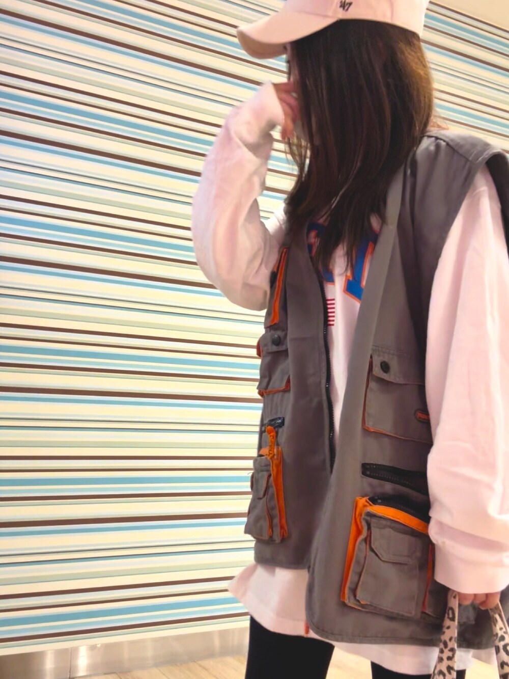 グレー系のベスト、ホワイト系のTシャツ/カットソー、ブルー系のスニーカーを着用したレディースの秋コーディネートの2枚目の写真