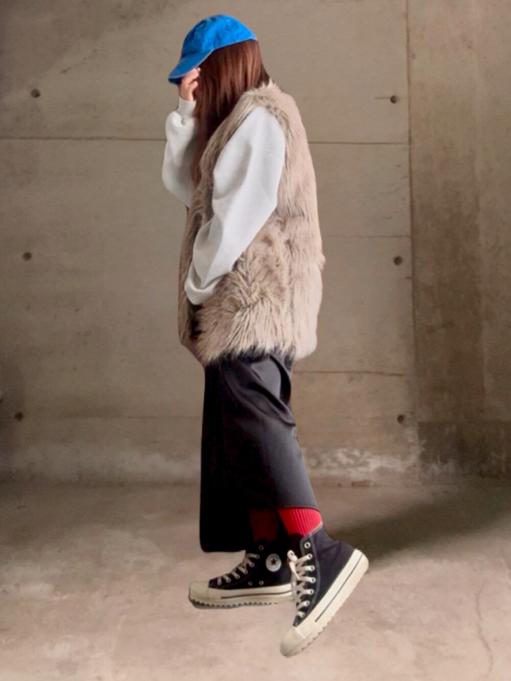 ブラック系のスカート、ブラック系のスニーカー、ベージュ系のベストを着用したレディースの冬コーディネートの3枚目の写真