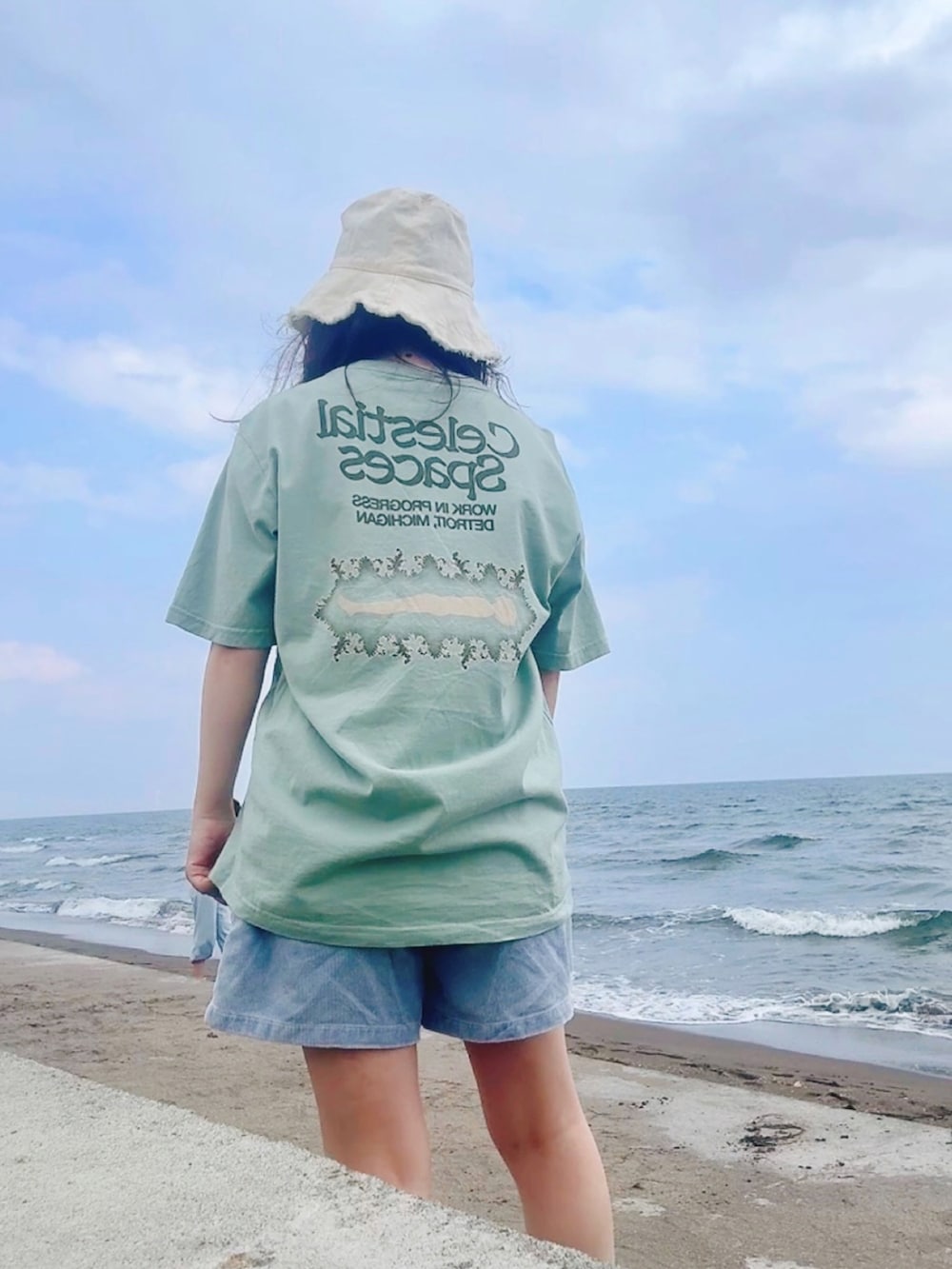グリーン系のTシャツ/カットソー、ブラック系のタンクトップ、ホワイト系のショルダーバッグを着用したレディースの秋コーディネートの2枚目の写真
