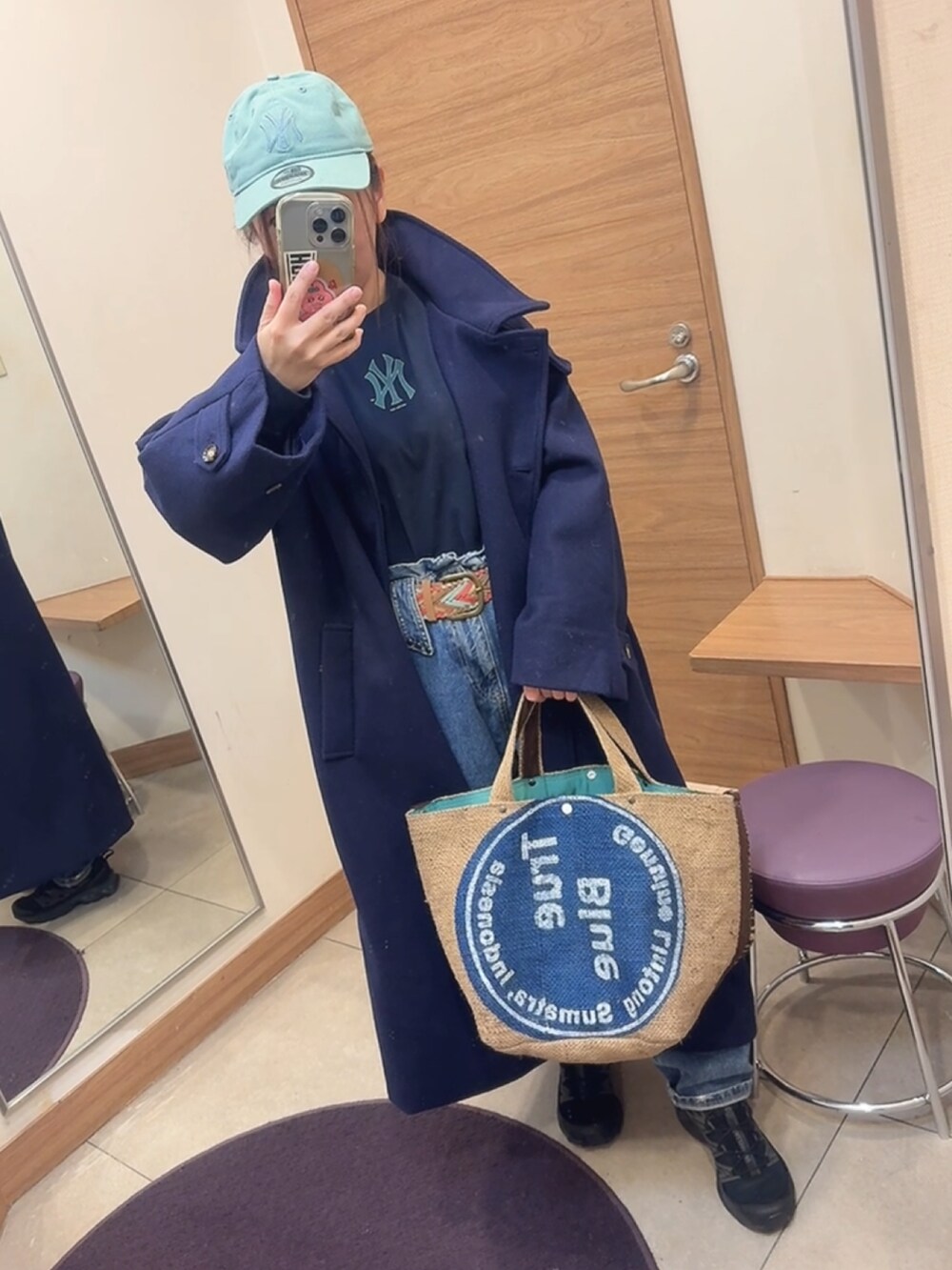 ブルー系のステンカラーコート、ブルー系のTシャツ/カットソー、ブラック系のスニーカーを着用したレディースの冬コーディネートの2枚目の写真