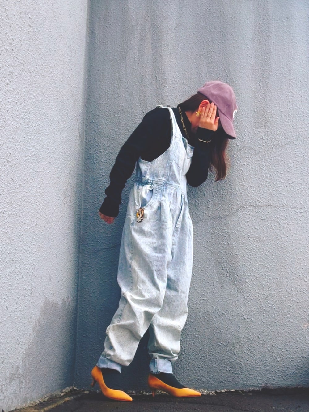 ブラック系のニット/セーター、ブルー系のサロペット/オーバーオール、イエロー系のパンプスを着用したレディースの冬コーディネートの2枚目の写真