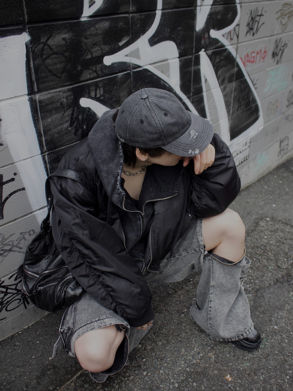 グレー系のデニムパンツ、ブラック系のスニーカー、ブラック系のMA-1を着用したメンズの冬コーディネートの3枚目の写真