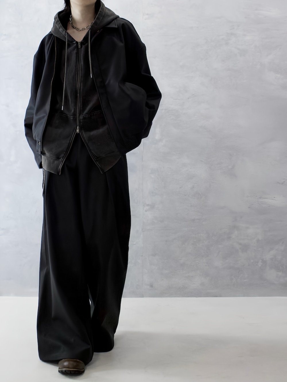 ブラウン系のパーカー、ブラック系のブーツ、ブラック系のブルゾンを着用したメンズの秋コーディネートの4枚目の写真