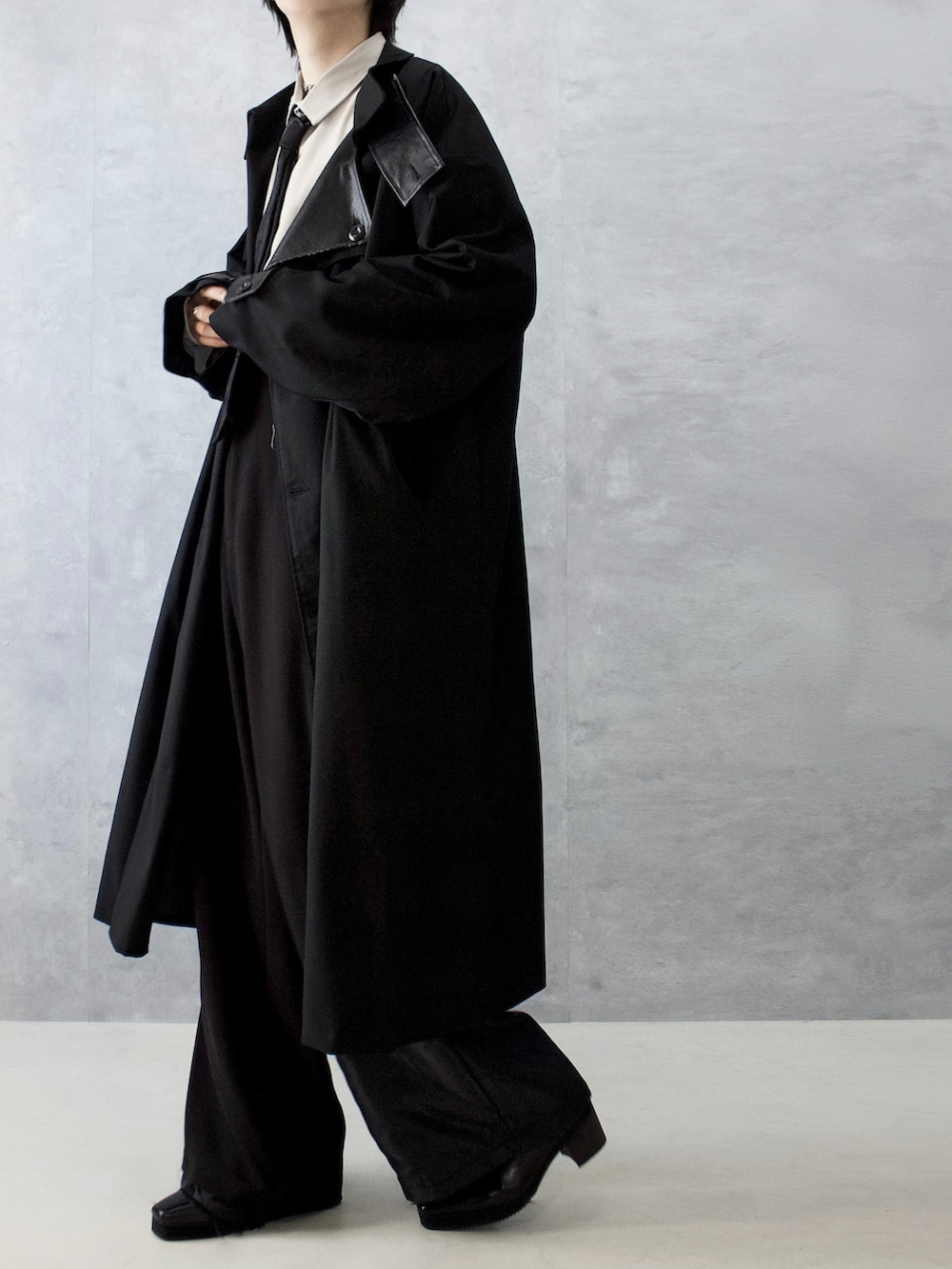 ブラック系のトレンチコート、ブラック系のスラックス、ベージュ系のシャツ/ブラウスを着用したメンズの秋コーディネートの4枚目の写真