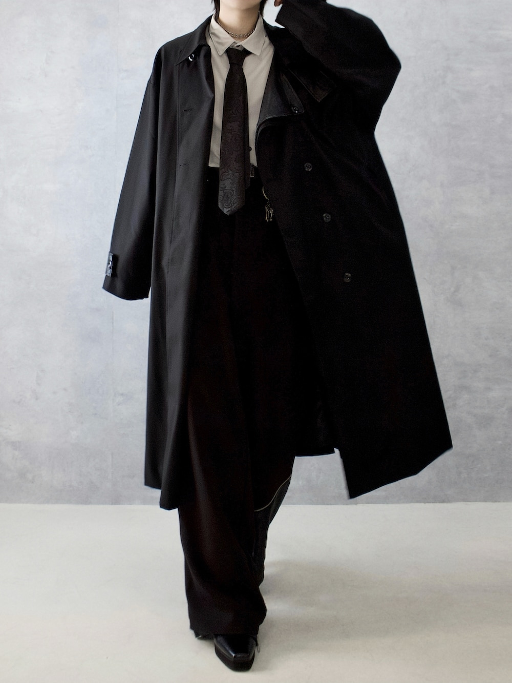 ブラック系のトレンチコート、ブラック系のスラックス、ベージュ系のシャツ/ブラウスを着用したメンズの秋コーディネートの5枚目の写真