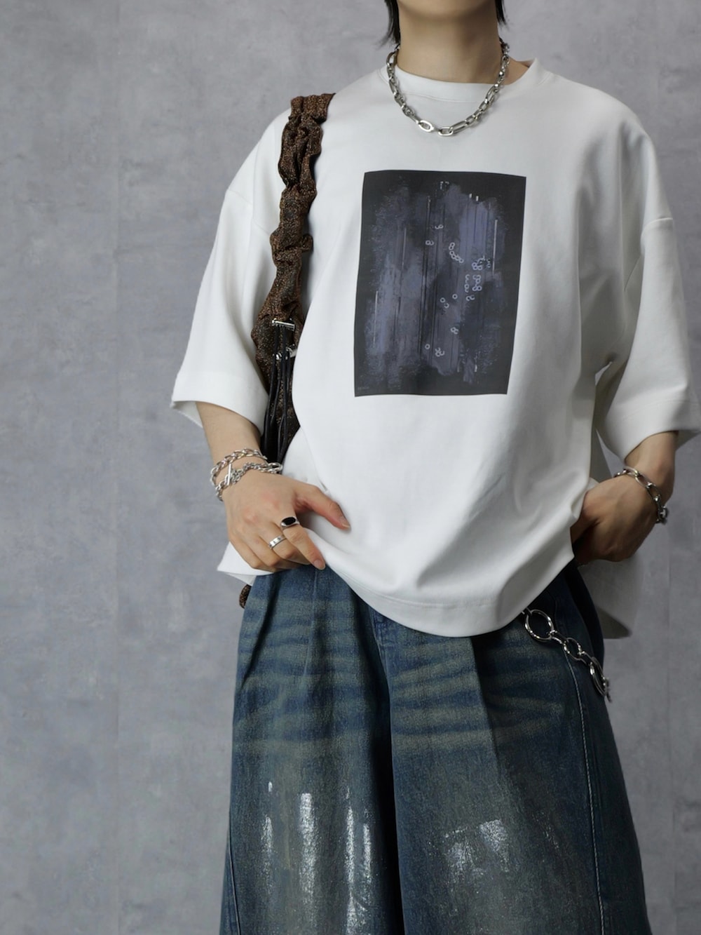 ホワイト系のTシャツ/カットソー、ブルー系のデニムパンツ、ブラウン系のトートバッグを着用したメンズの春コーディネートの3枚目の写真