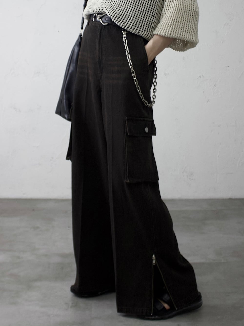 グレー系のトップス、ブラック系のデニムパンツ、ブラック系のショルダーバッグを着用したメンズの春コーディネートの2枚目の写真