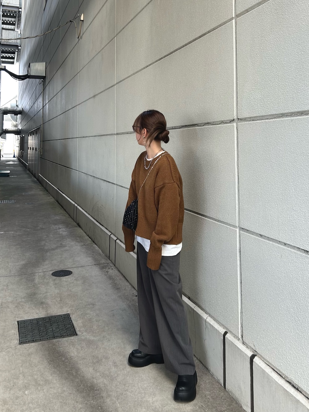 イエロー系のニット/セーター、ブラック系のブーツ、ホワイト系のTシャツ/カットソーを着用したレディースの秋コーディネートの2枚目の写真