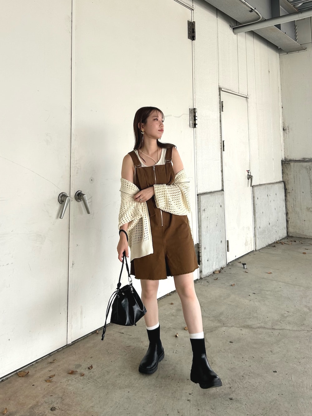 ブラウン系のサロペット/オーバーオール、ホワイト系のパーカー、ブラック系のショルダーバッグを着用したレディースの秋コーディネートの3枚目の写真