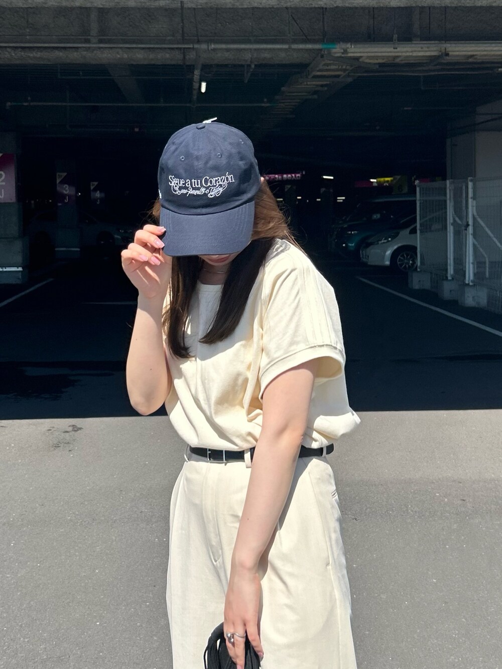 ホワイト系のTシャツ/カットソー、ブラック系のトートバッグ、ブラック系のサンダルを着用したレディースの夏コーディネートの3枚目の写真