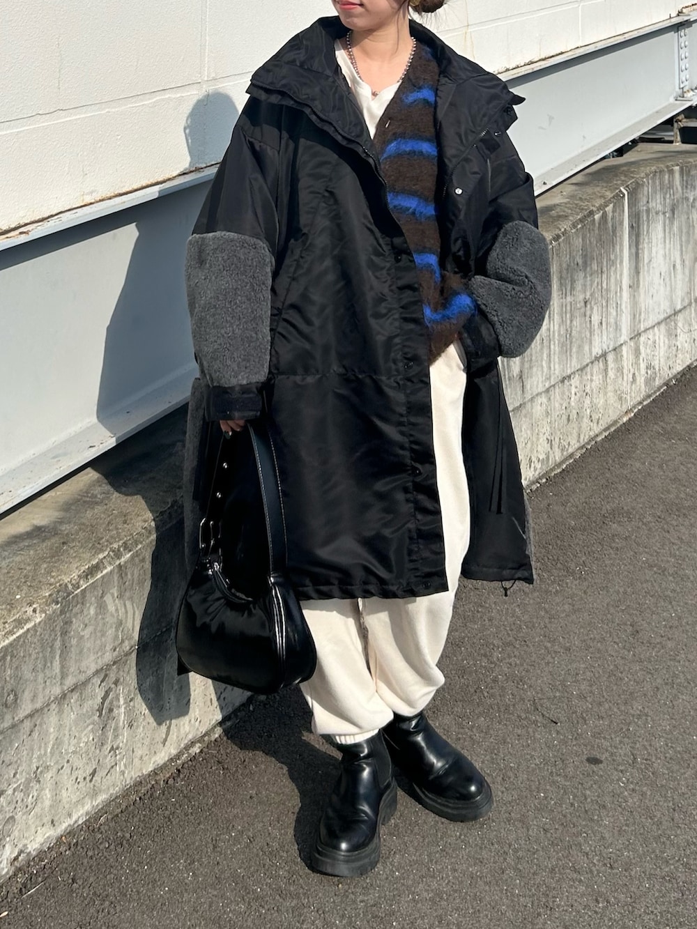 ブラック系のモッズコート、ブラウン系のカーディガン/ボレロ、ブラック系のトートバッグを着用したレディースの冬コーディネートの2枚目の写真