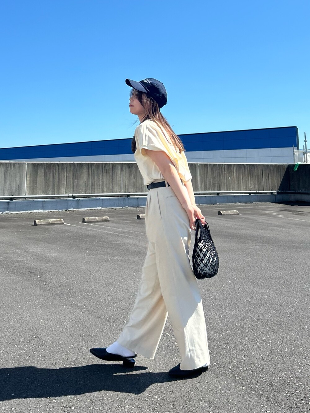 ホワイト系のTシャツ/カットソー、ブラック系のトートバッグ、ブラック系のサンダルを着用したレディースの夏コーディネートの2枚目の写真