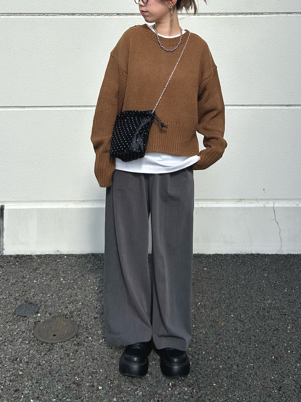 イエロー系のニット/セーター、ブラック系のブーツ、ホワイト系のTシャツ/カットソーを着用したレディースの秋コーディネートの4枚目の写真