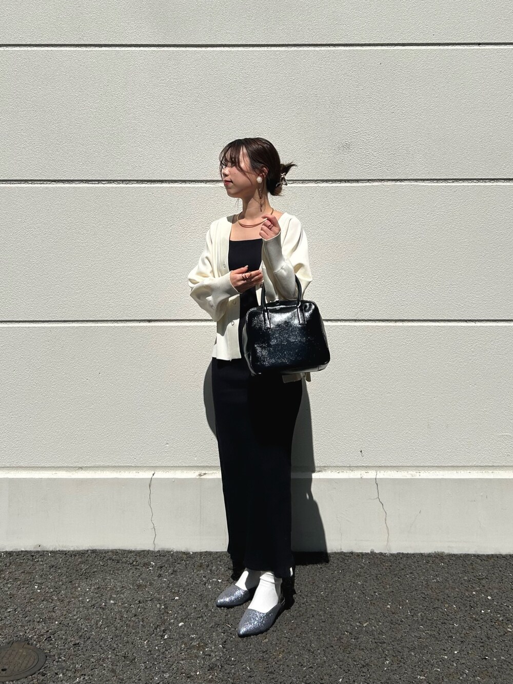 ホワイト系のカーディガン/ボレロ、ブラック系のワンピース、グレー系のサンダルを着用したレディースの春コーディネートの3枚目の写真