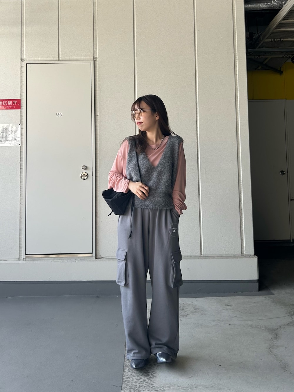 グレー系のベスト、ピンク系のTシャツ/カットソー、グレー系のスウェットパンツを着用したレディースの春コーディネートの2枚目の写真