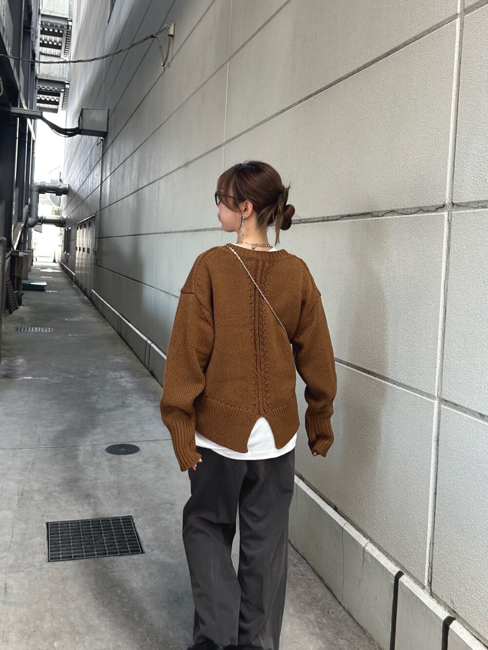 イエロー系のニット/セーター、ブラック系のブーツ、ホワイト系のTシャツ/カットソーを着用したレディースの秋コーディネートの3枚目の写真