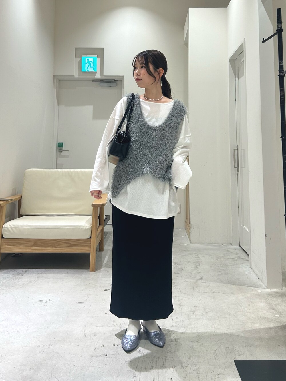 ホワイト系のTシャツ/カットソー、グレー系のベスト、ブラック系のスカートを着用したレディースの春コーディネートの2枚目の写真
