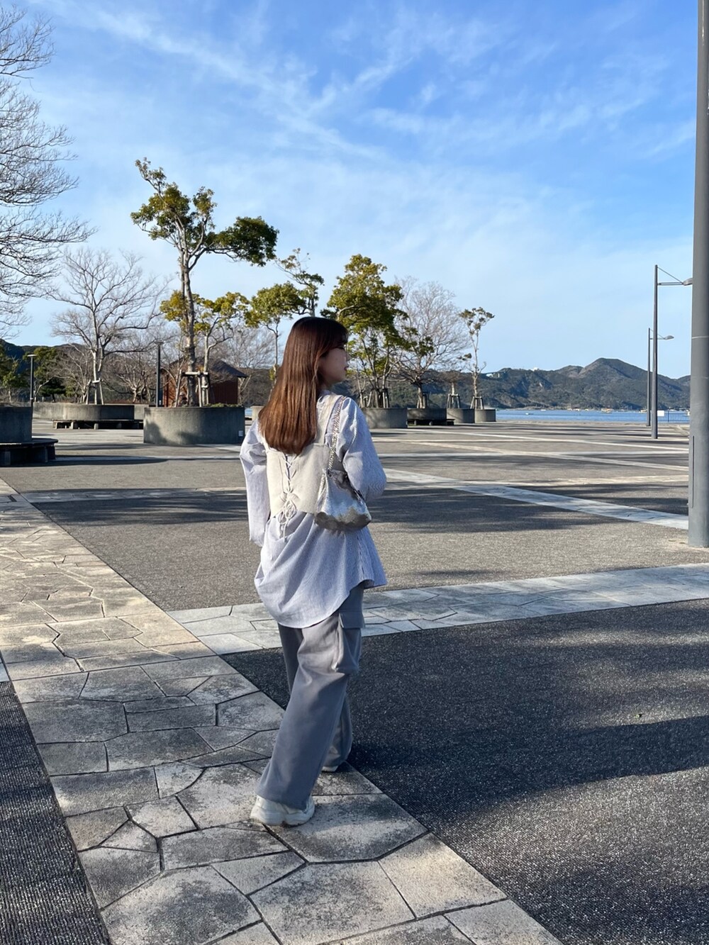 グレー系のスウェットパンツ、ゴールド系のショルダーバッグを着用したレディースの春コーディネートの2枚目の写真