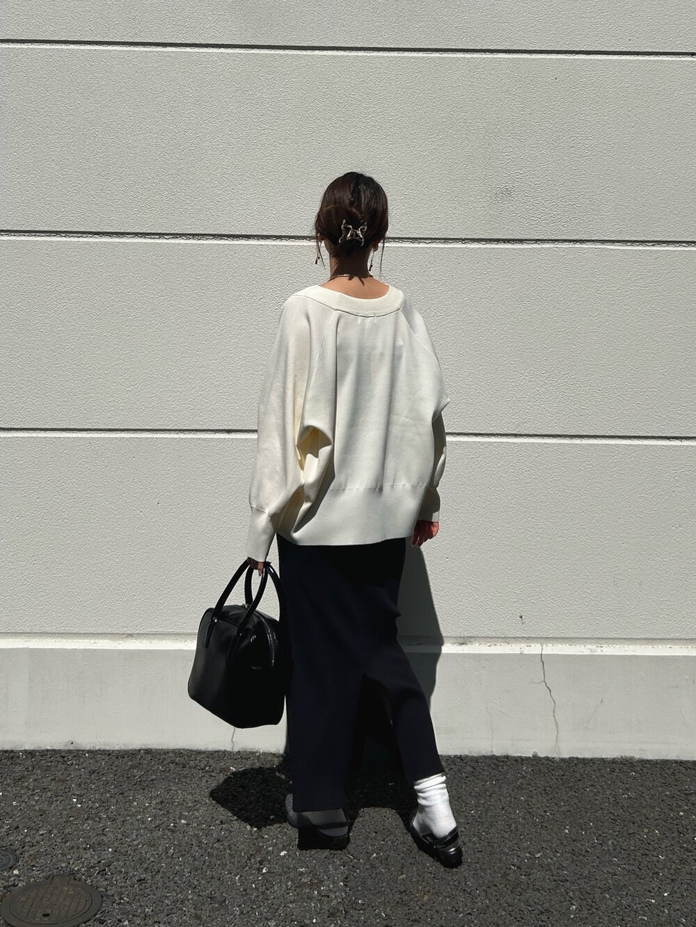 ホワイト系のカーディガン/ボレロ、ブラック系のワンピース、グレー系のサンダルを着用したレディースの春コーディネートの2枚目の写真