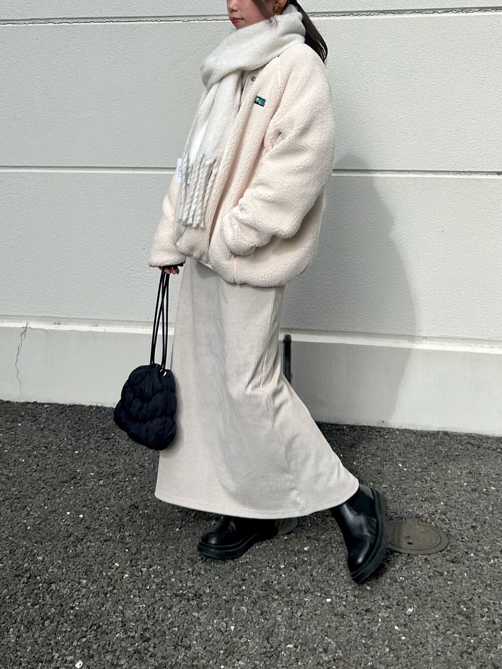 ホワイト系のブルゾン、ホワイト系のワンピース、ブラック系のショルダーバッグを着用したレディースの冬コーディネートの2枚目の写真