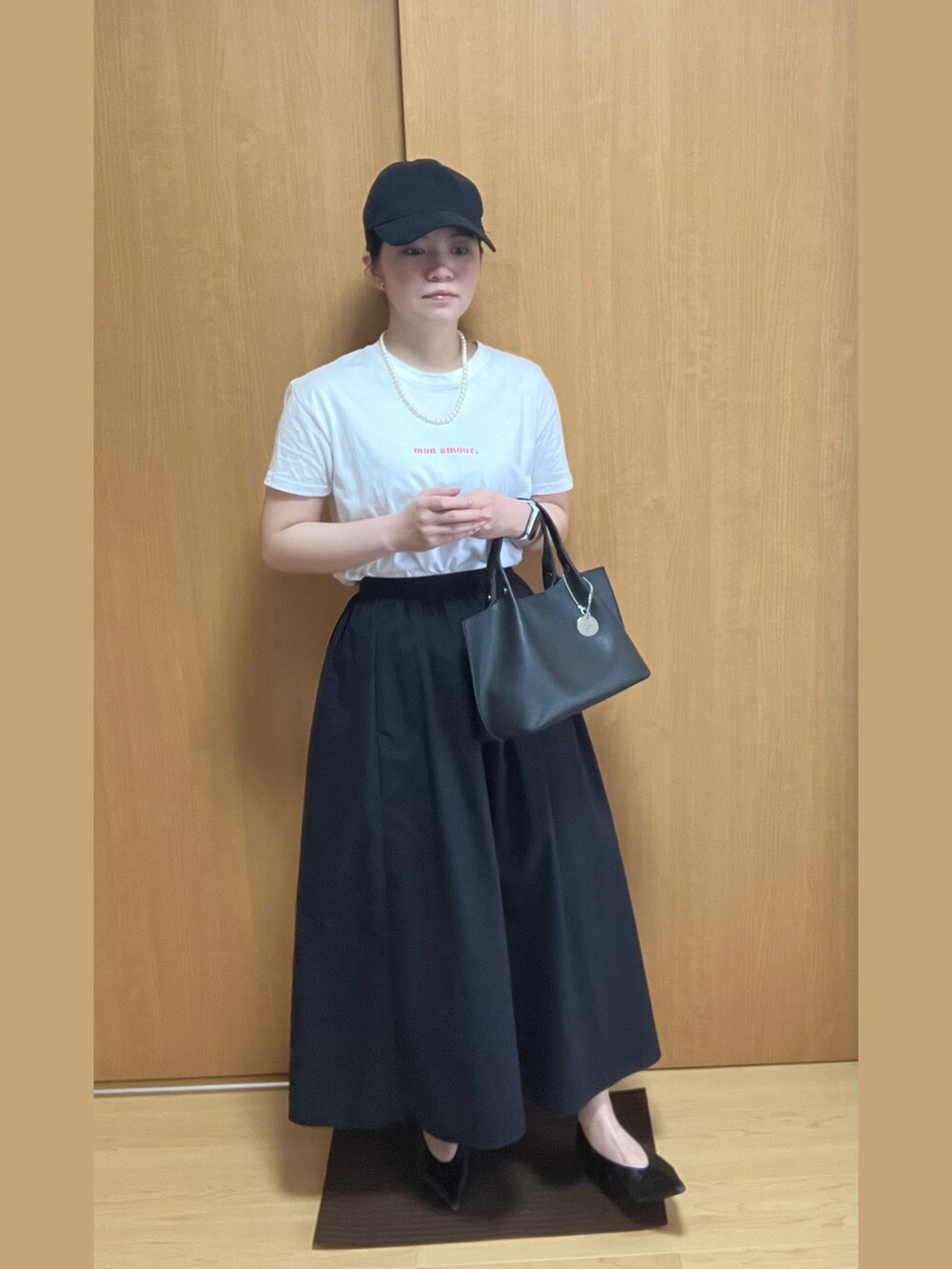 ホワイト系のTシャツ/カットソー、ブラック系のスカート、ブラック系のパンプスを着用したレディースの夏コーディネートの2枚目の写真