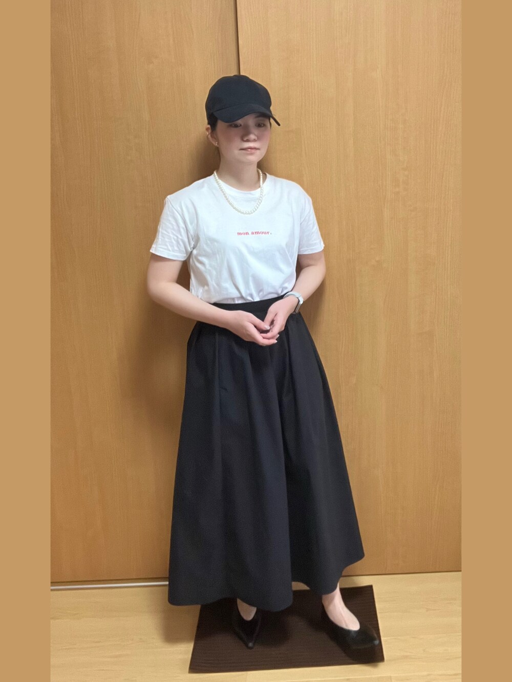 ホワイト系のTシャツ/カットソー、ブラック系のスカート、ブラック系のパンプスを着用したレディースの夏コーディネートの4枚目の写真