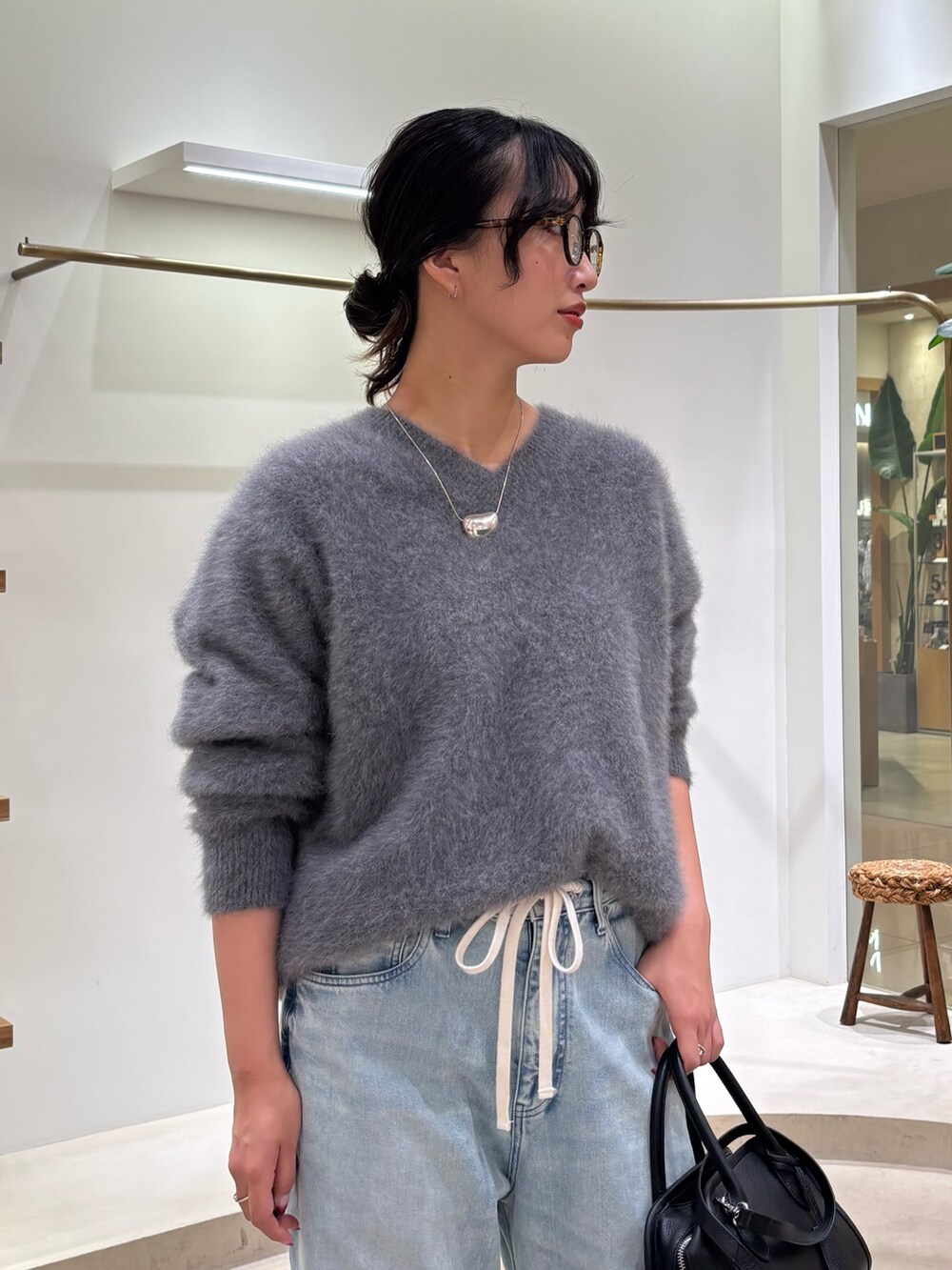 ブルー系のデニムパンツ、ブラック系のボストンバッグ、グレー系のニット/セーターを着用したレディースの秋コーディネートの5枚目の写真