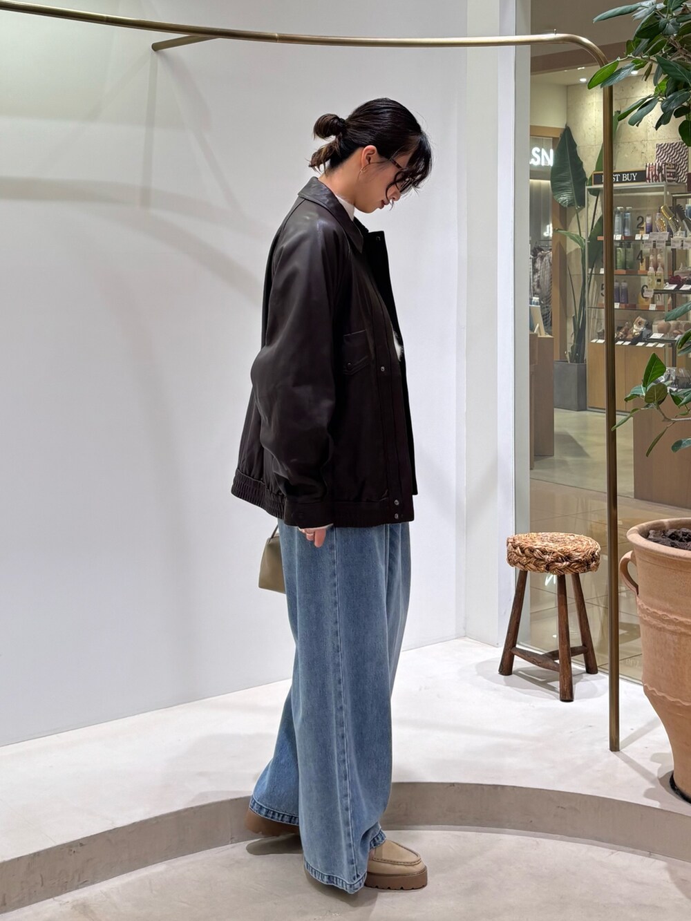 ブラウン系のブルゾン、ホワイト系のニット/セーター、ブルー系のデニムパンツを着用したレディースの秋コーディネートの5枚目の写真