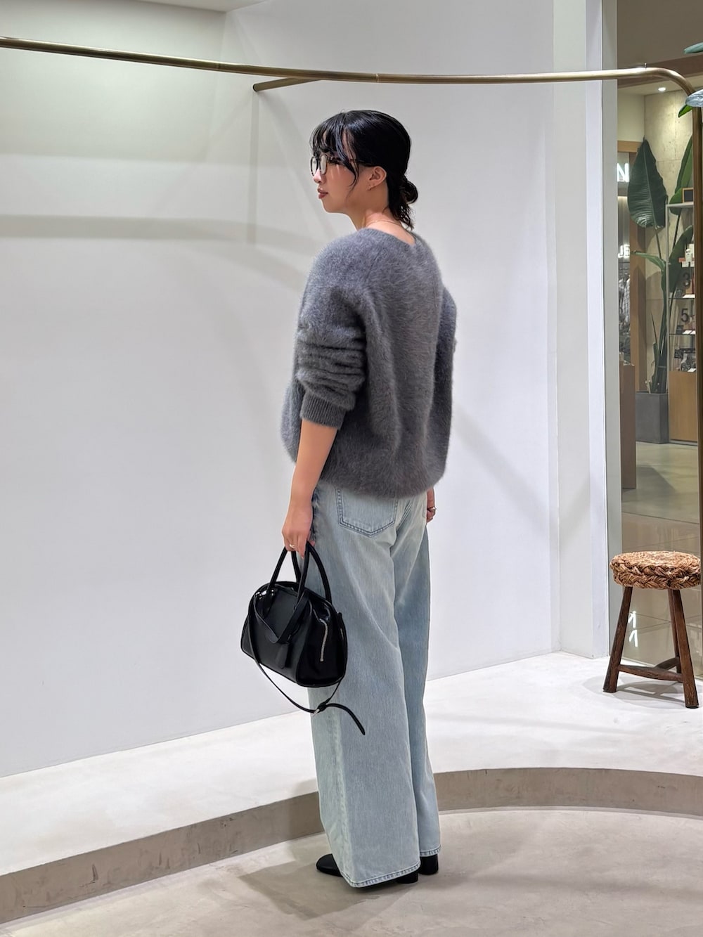 ブルー系のデニムパンツ、ブラック系のボストンバッグ、グレー系のニット/セーターを着用したレディースの秋コーディネートの2枚目の写真