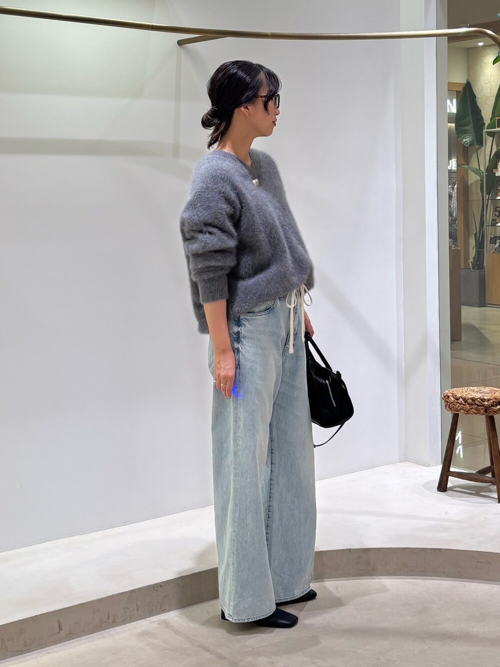 ブルー系のデニムパンツ、ブラック系のボストンバッグ、グレー系のニット/セーターを着用したレディースの秋コーディネートの4枚目の写真