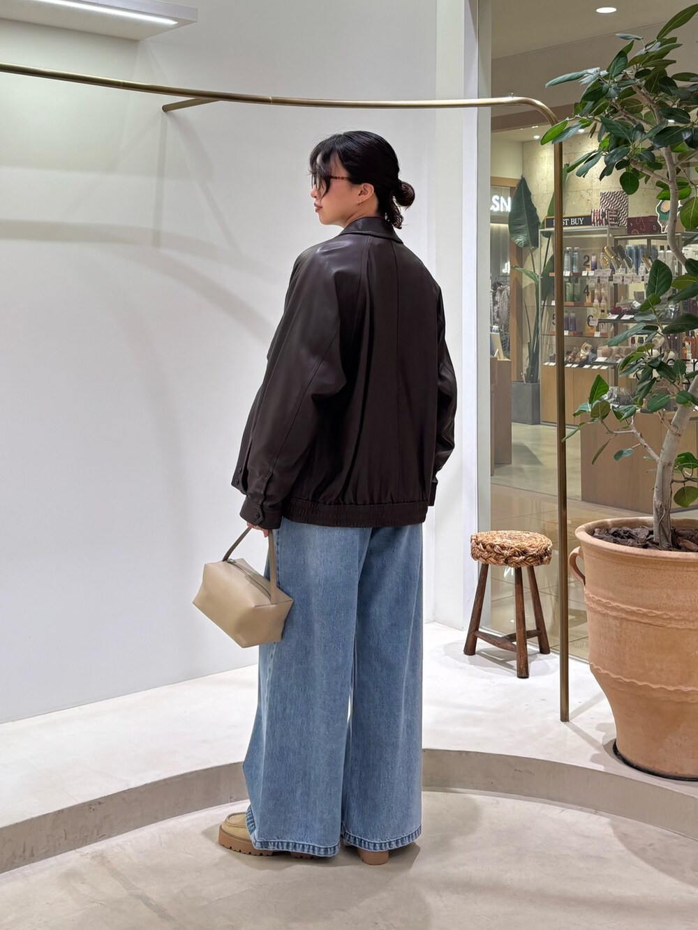 ブラウン系のブルゾン、ホワイト系のニット/セーター、ブルー系のデニムパンツを着用したレディースの秋コーディネートの3枚目の写真