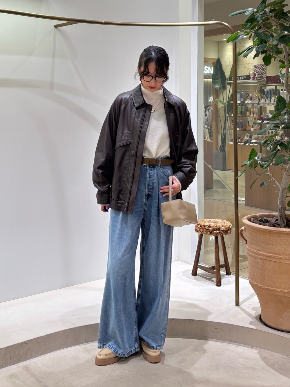 ブラウン系のブルゾン、ホワイト系のニット/セーター、ブルー系のデニムパンツを着用したレディースの秋コーディネートの2枚目の写真
