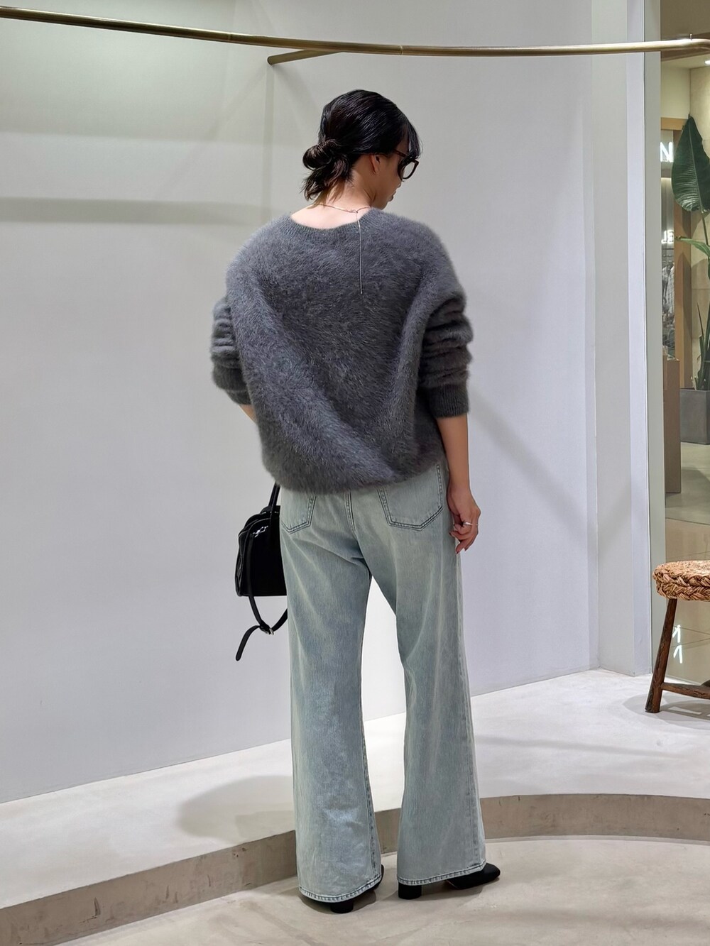 ブルー系のデニムパンツ、ブラック系のボストンバッグ、グレー系のニット/セーターを着用したレディースの秋コーディネートの3枚目の写真