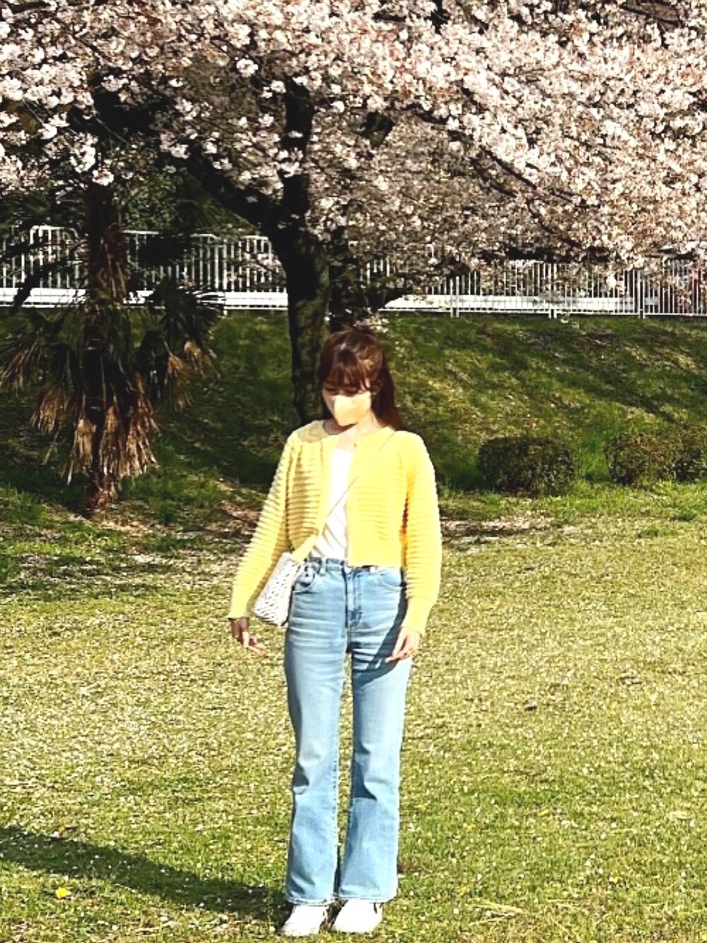 ブルー系のデニムパンツ、イエロー系のカーディガン/ボレロ、ホワイト系のショルダーバッグを着用したレディースの春コーディネートの2枚目の写真