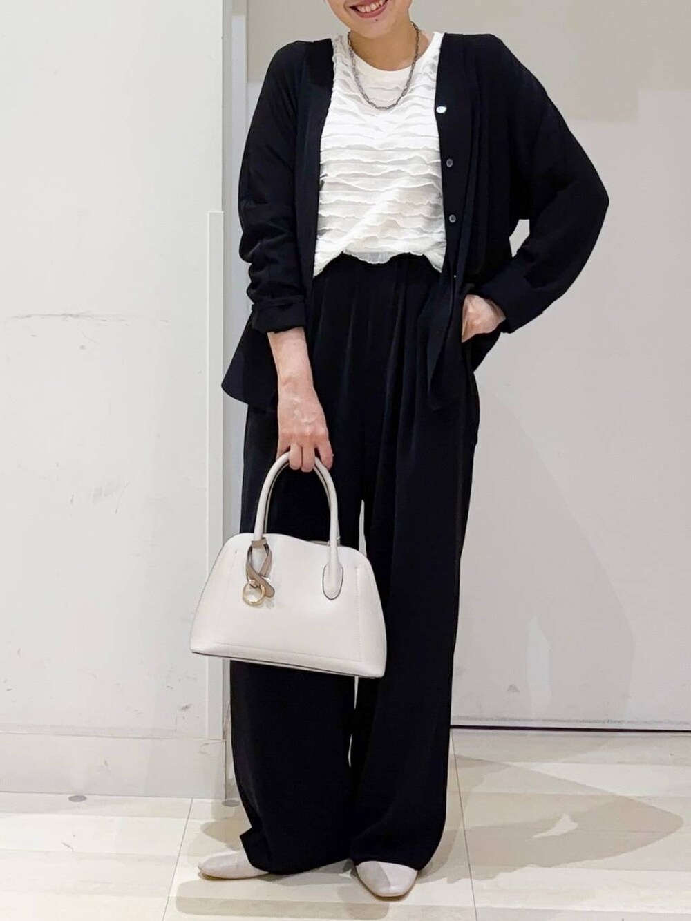 ベージュ系のパンプス、ホワイト系のショルダーバッグ、ブラック系のその他パンツを着用したレディースの秋コーディネートの2枚目の写真