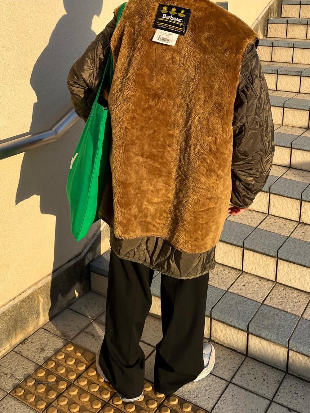 ブラック系のパンツ、グリーン系のモッズコート、ブラウン系のベストを着用したレディースの冬コーディネートの4枚目の写真