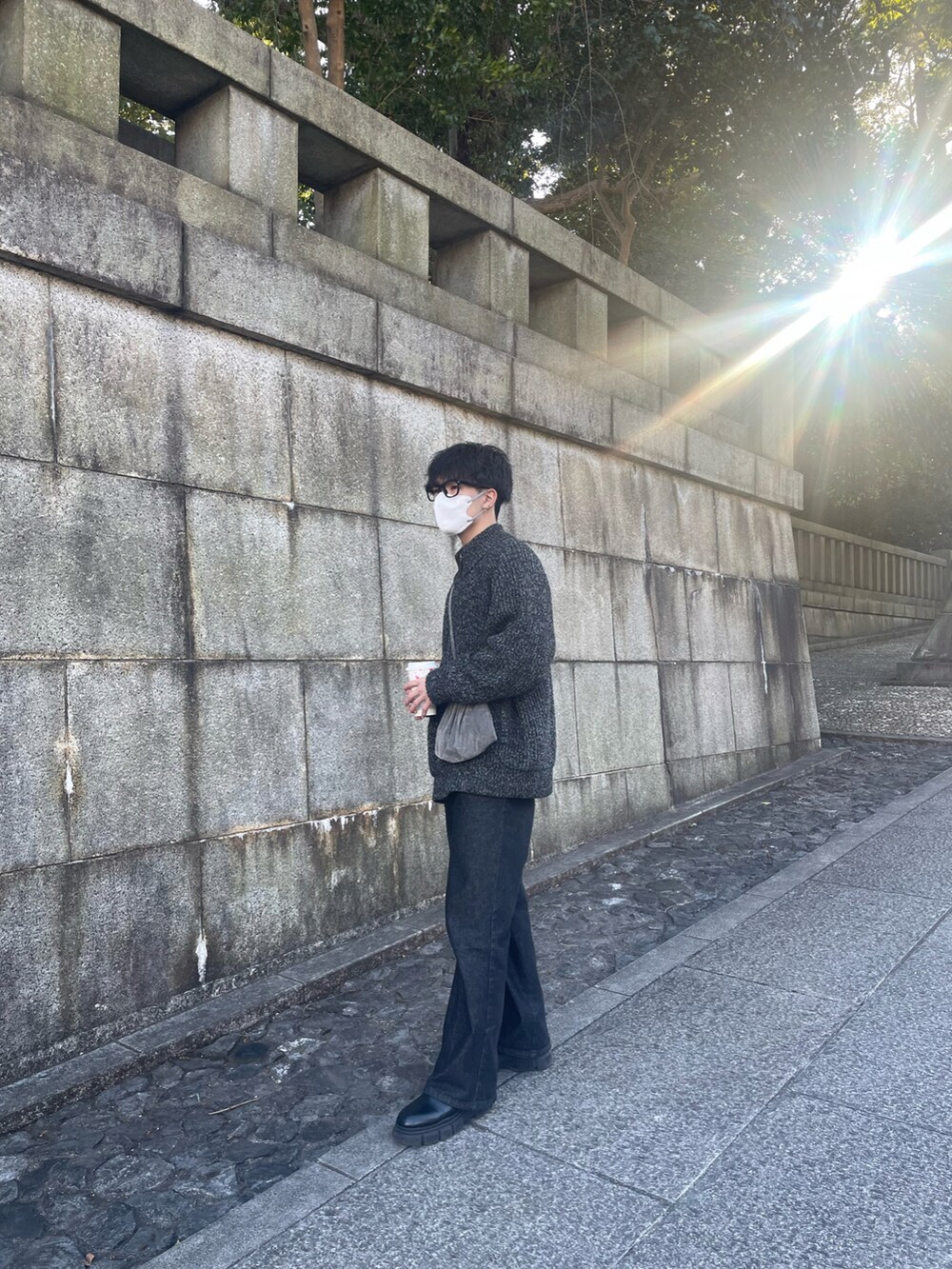 ブラック系のデニムパンツ、ブラック系のブーツ、グレー系のニット/セーターを着用したメンズの冬コーディネートの2枚目の写真