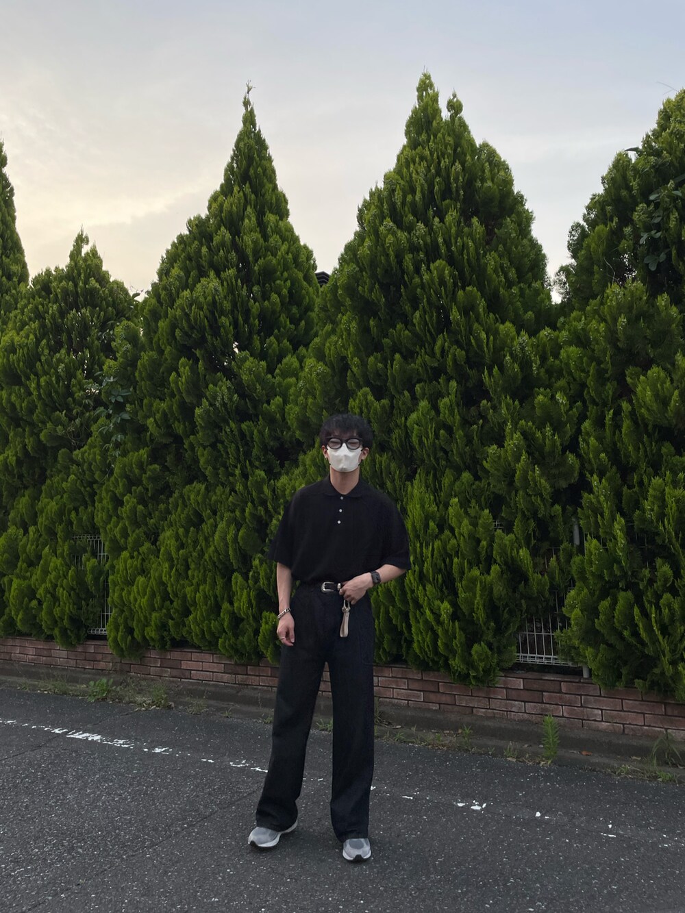 ブラック系のポロシャツ、ブラック系のデニムパンツ、グレー系のスニーカーを着用したメンズの夏コーディネートの3枚目の写真