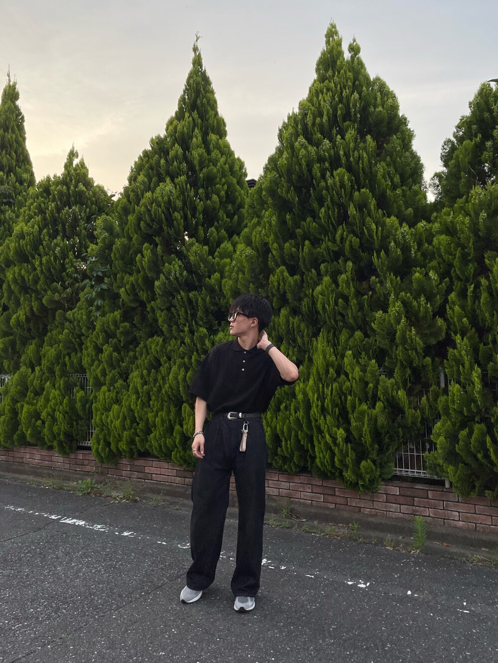 ブラック系のポロシャツ、ブラック系のデニムパンツ、グレー系のスニーカーを着用したメンズの夏コーディネートの2枚目の写真