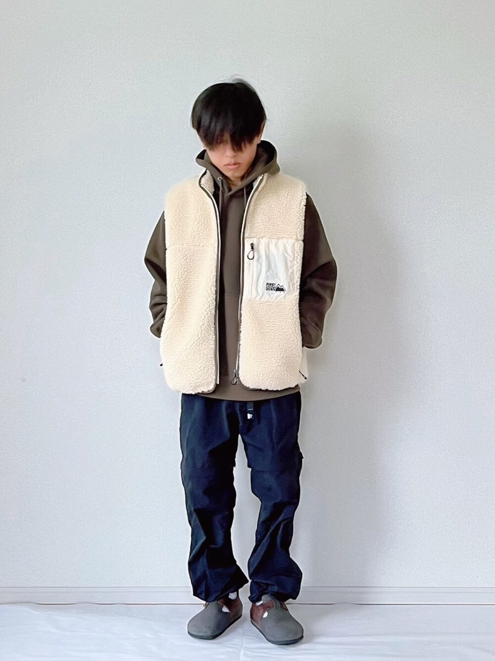 グリーン系のパーカー、ブラック系のその他パンツ、ホワイト系のベストを着用したメンズの秋コーディネートの2枚目の写真