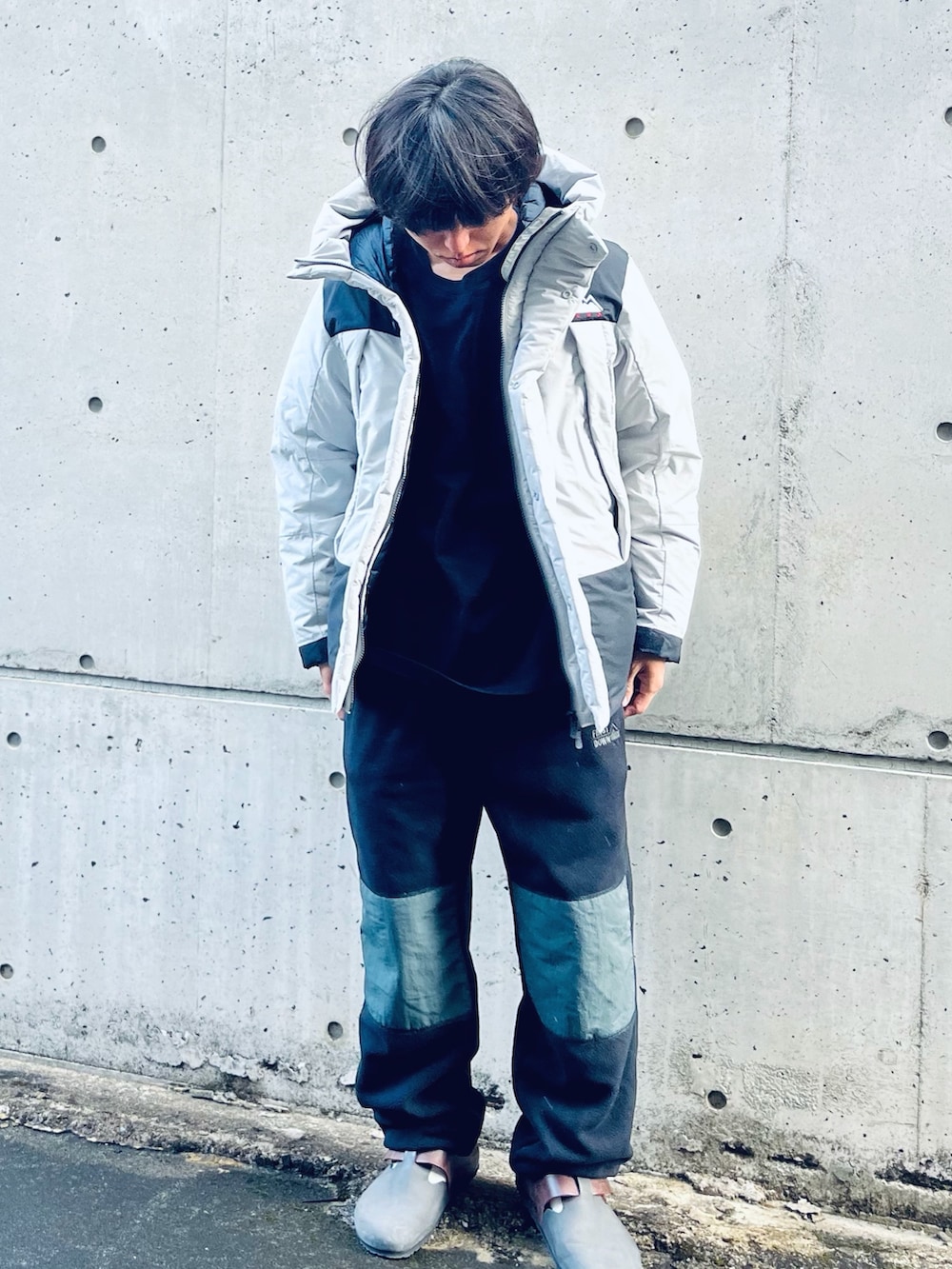 グレー系のダウンジャケット/コート、ブラウン系のスリッポン、ブラック系のその他パンツを着用したメンズの冬コーディネートの2枚目の写真