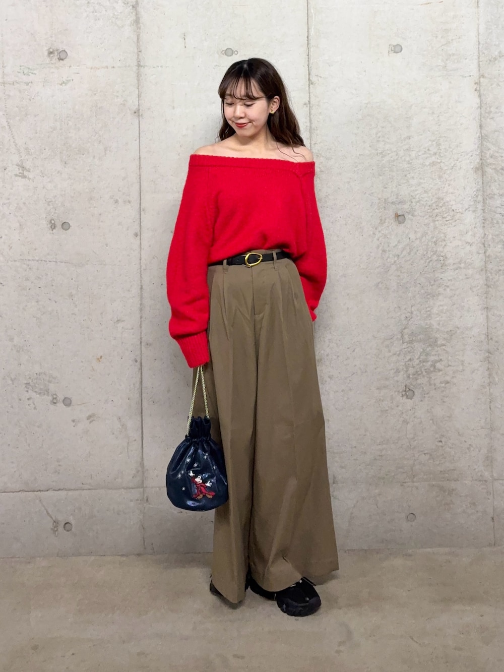 レッド系のニット/セーター、ベージュ系のチノパンツ、ブルー系のショルダーバッグを着用したレディースの冬コーディネートの4枚目の写真