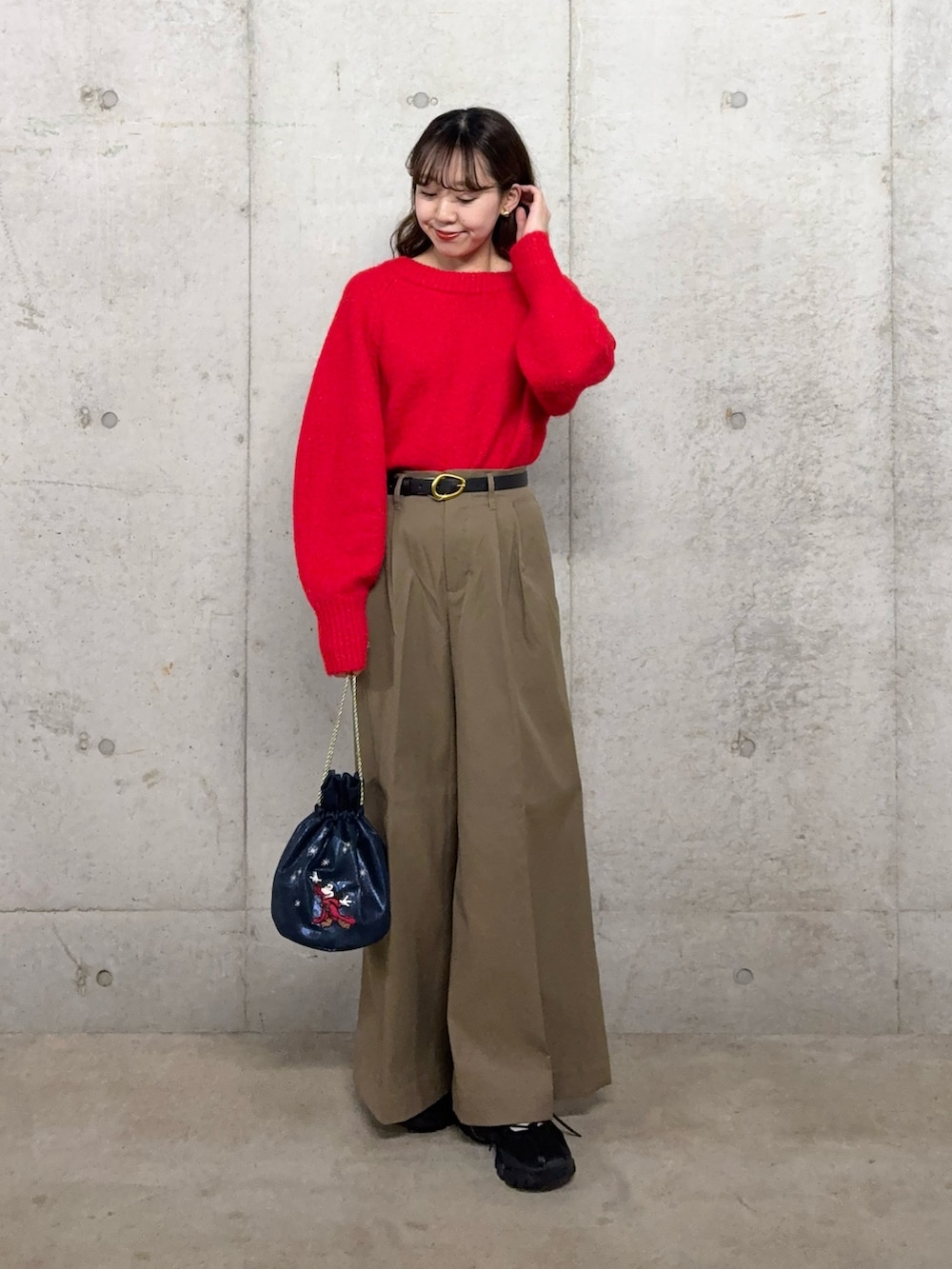 レッド系のニット/セーター、ベージュ系のチノパンツ、ブルー系のショルダーバッグを着用したレディースの冬コーディネートの3枚目の写真
